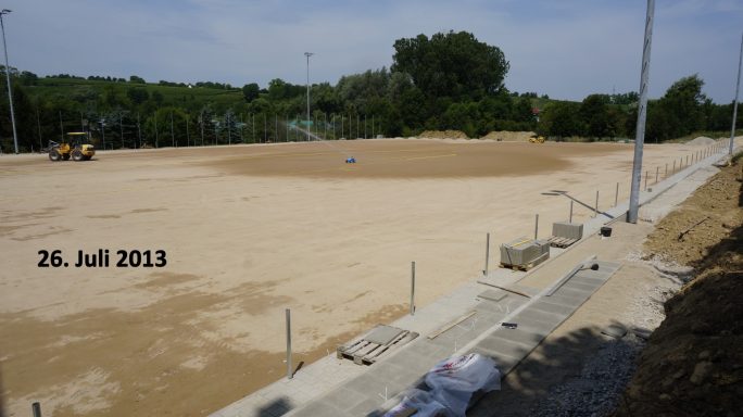 Baustelle mit leeren Sandflächen und gerade verlegtem Pflastersteinrand.