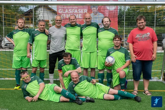 Gruppensfoto einer Fußballmannschaft in leuchtend grünen Trikots auf dem Platz.