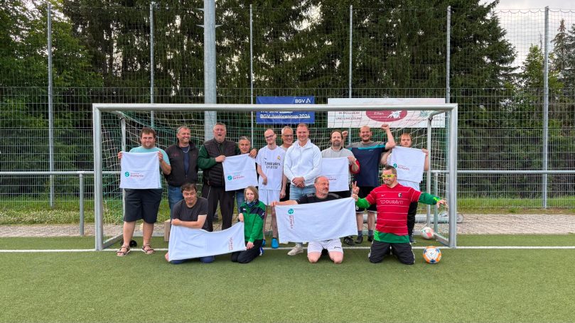Gruppenshooting mit Fußballspielern vor dem Tor, jeder hält ein Schild.