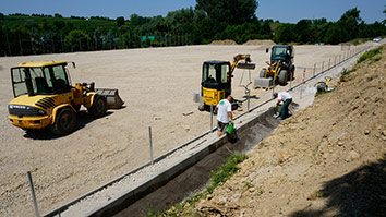 Bauarbeiten auf einem geräumigen Gelände mit Baumaschinen und Arbeitern.