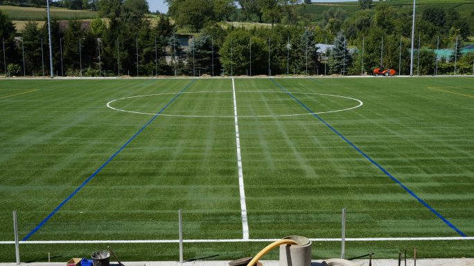 Sportplatz mit grünem Rasen und weißen Linien für ein Fußballfeld.